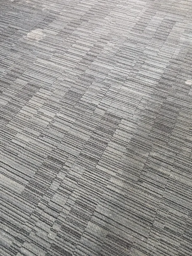 The same restaurant's carpet tile after cleaning, even color with the pattern clear again