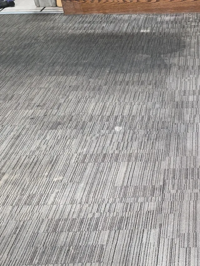 Commercial carpet tile in a restaurant dining room before cleaning, gray and dull with traffic lanes